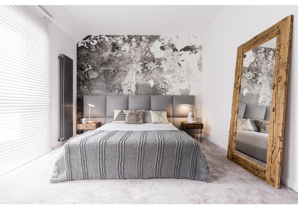 A modern grey and white bedroom with a large freestanding mirror to the right.