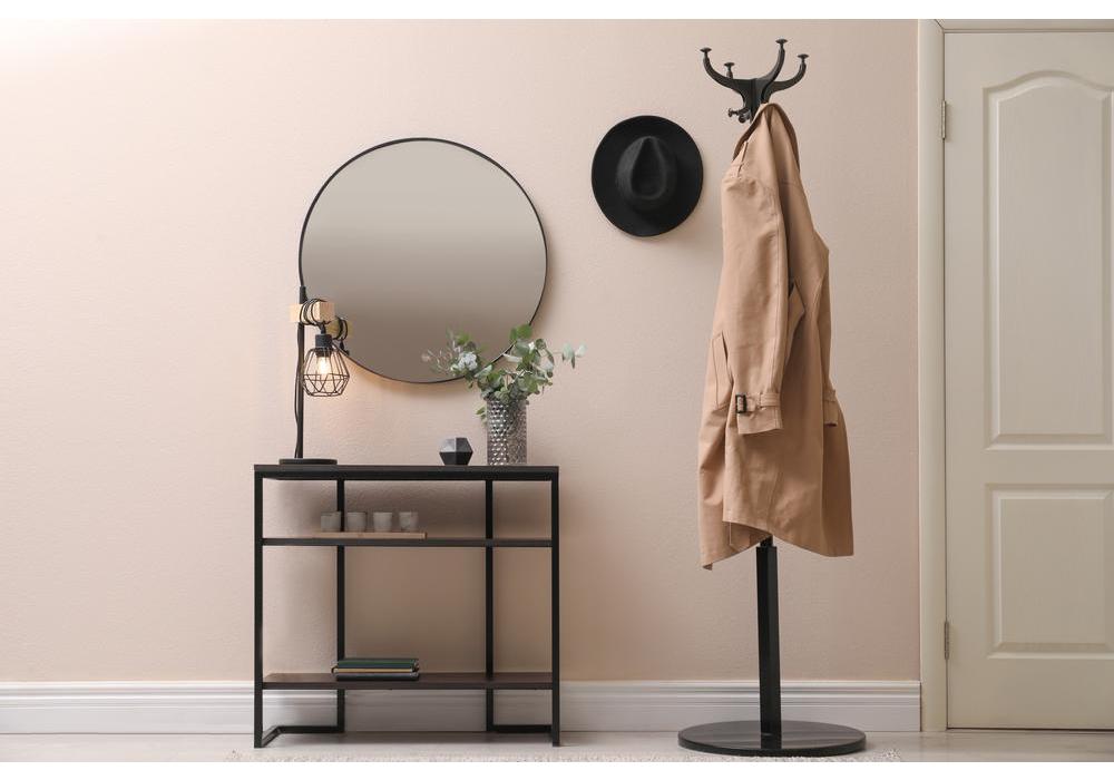 A neat, modern hallway featuring a simple coat rack, dressing table and round mirror. 