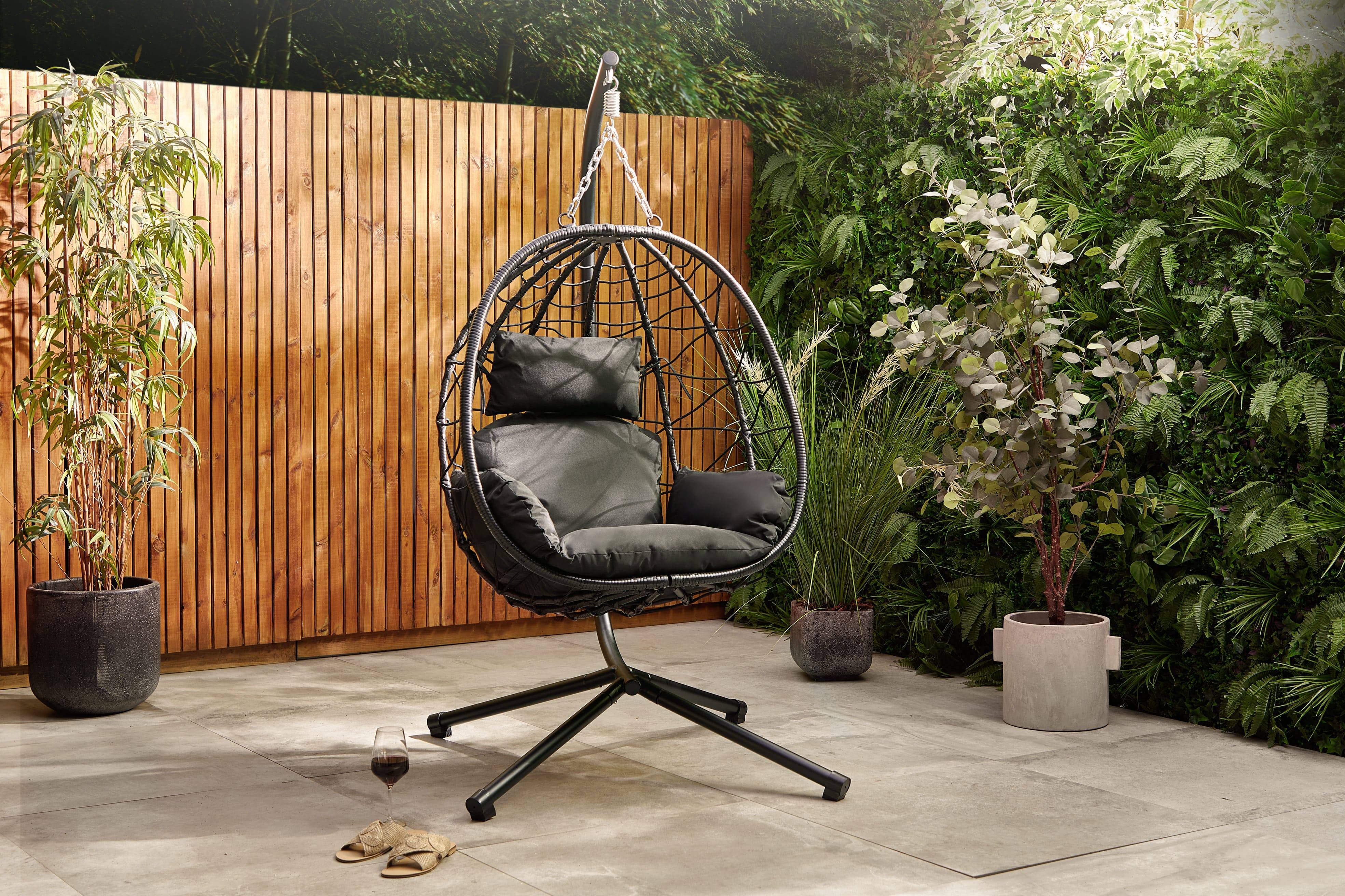 Black rattan egg chair on a stone garden patio