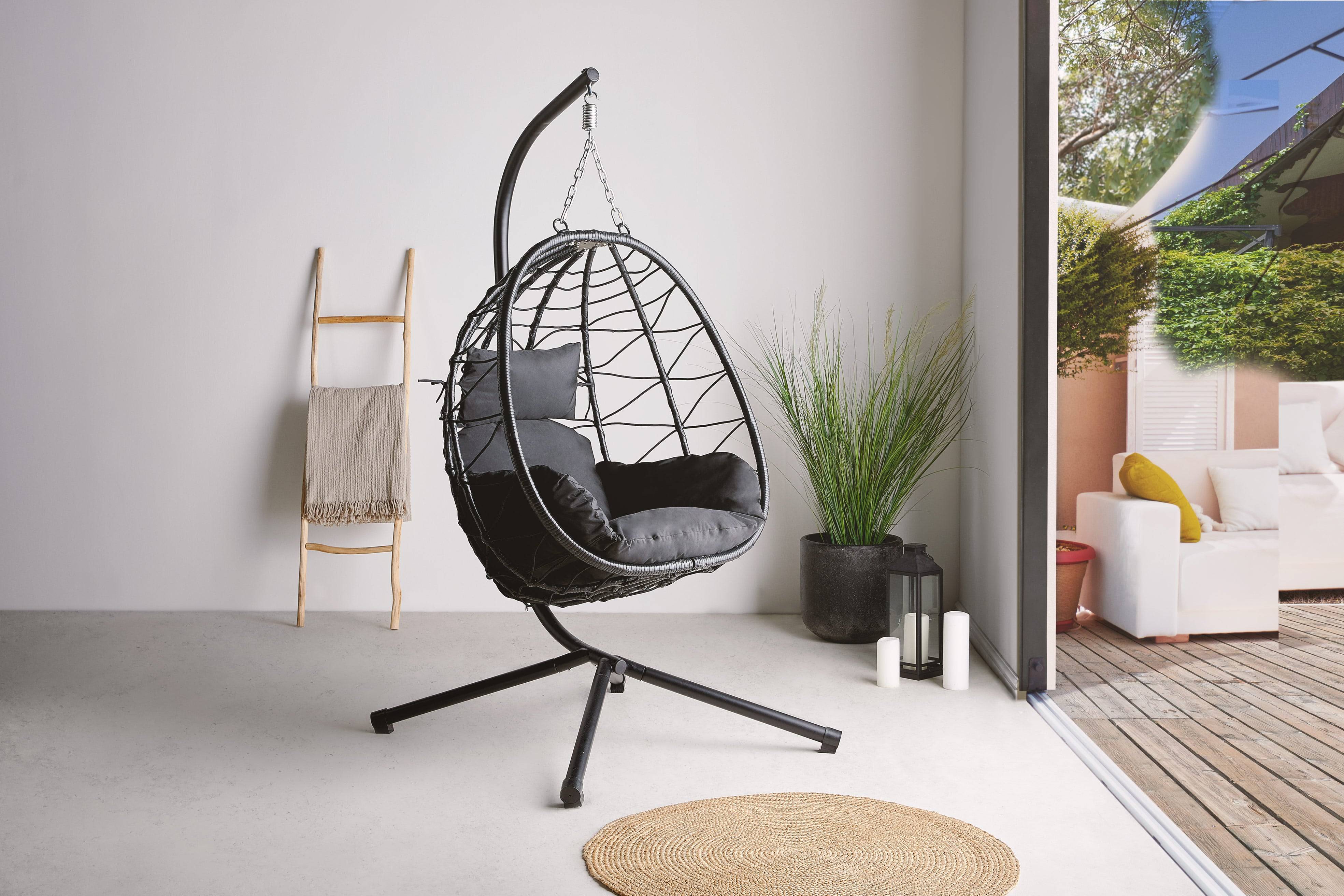 Black rattan egg chair indoors facing open patio doors