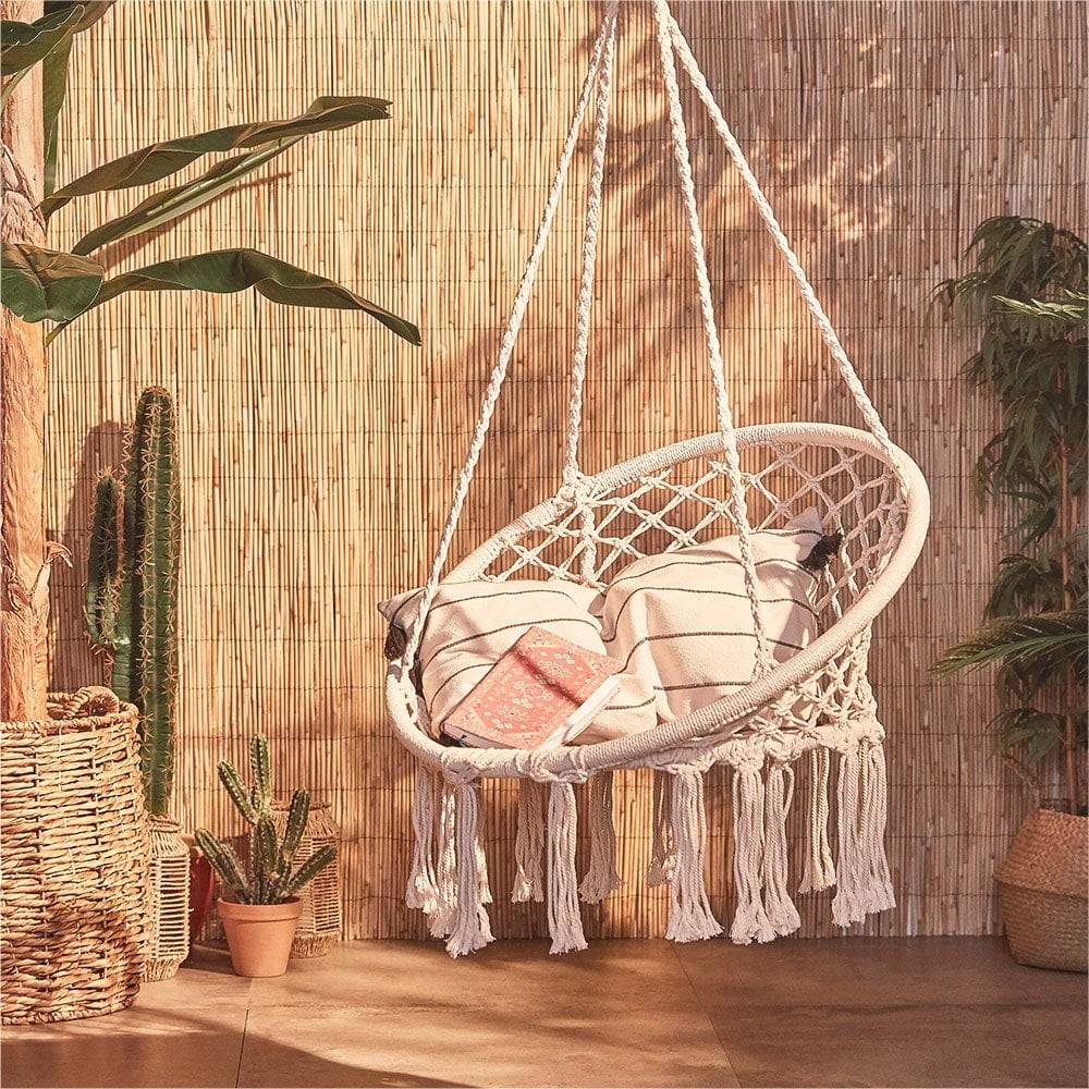 Boho-style hanging chair suspended above wooden garden decking
