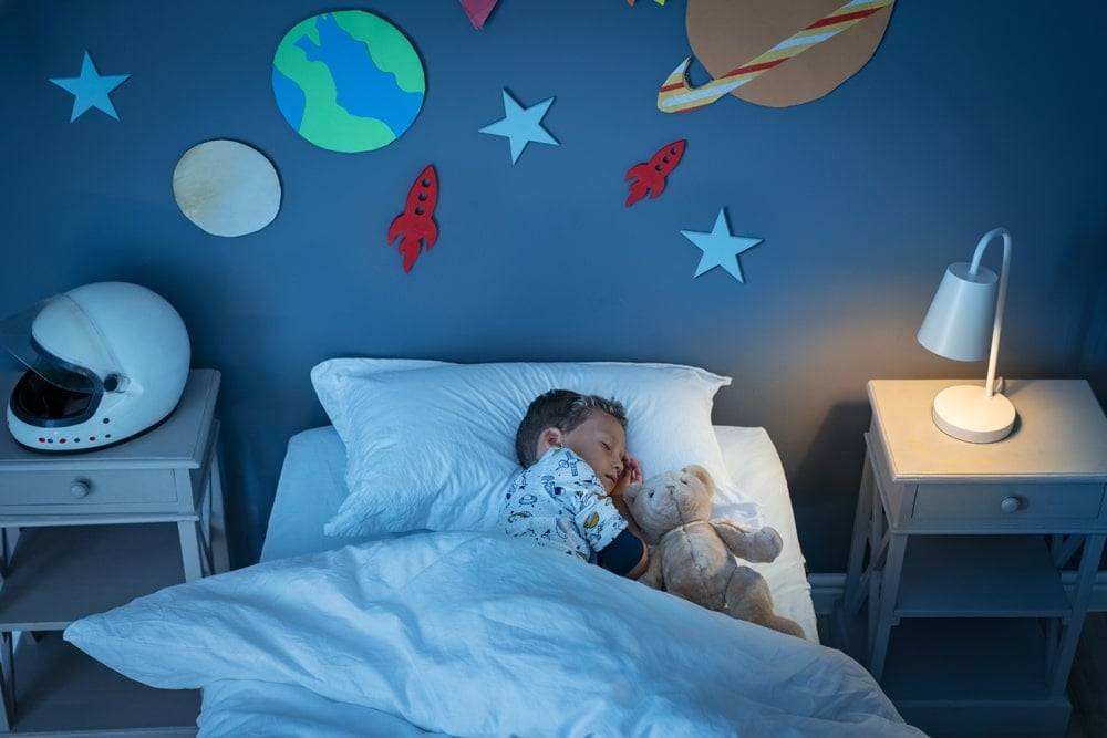 Boy sleeping in a space-themed bedroom