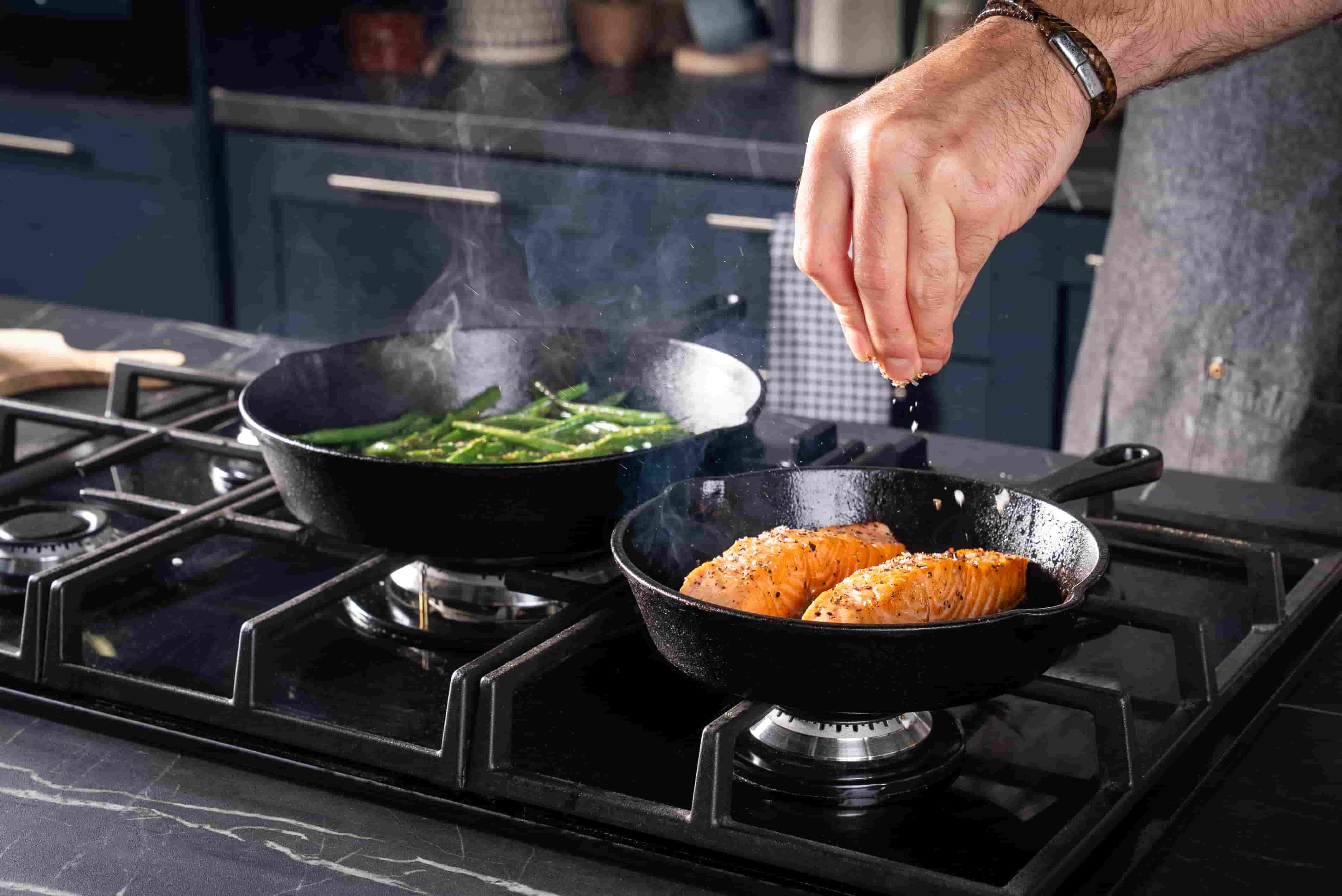 Man seasoning food using Vonshef cast iron skillets