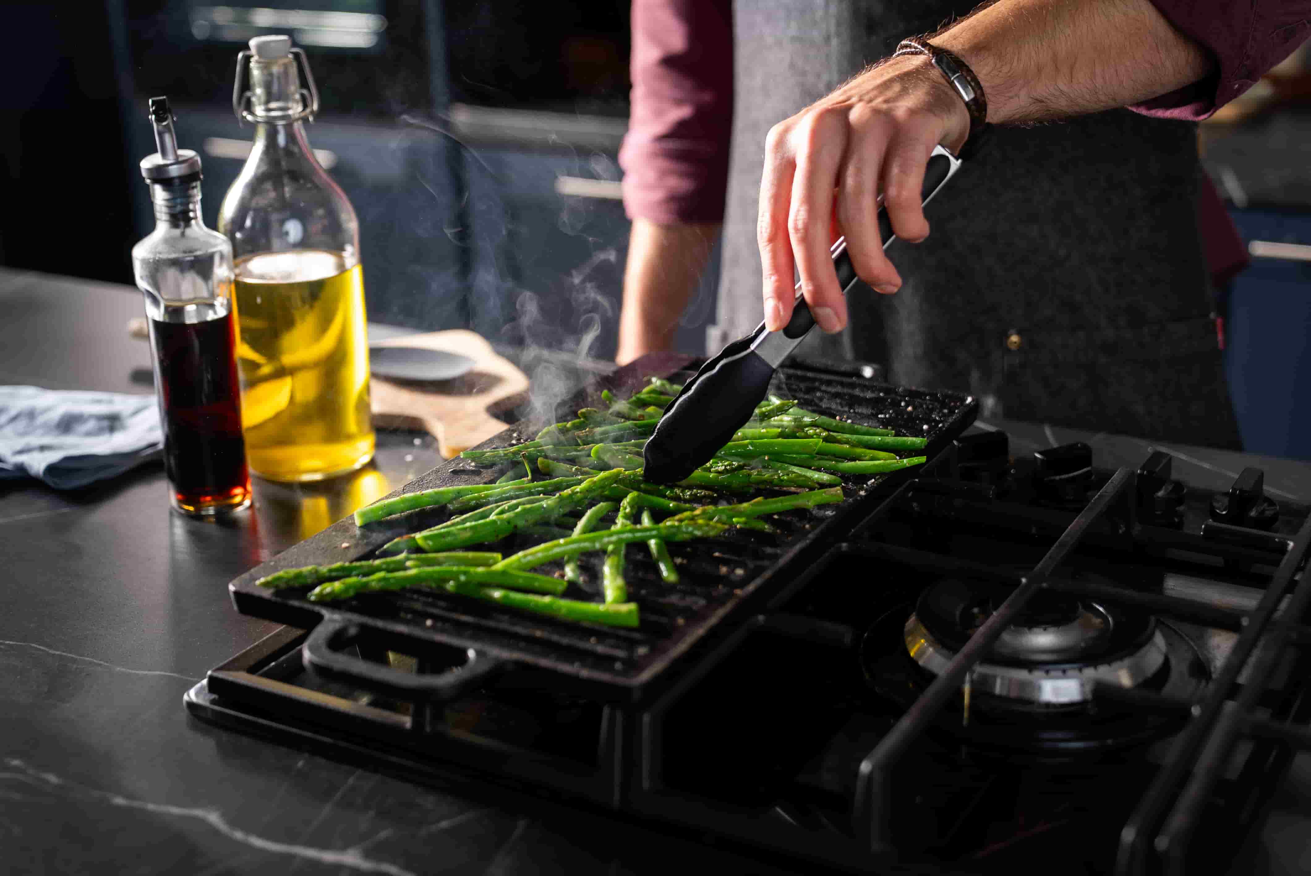 Man cookling asparagus on Vonshef cast iron pan