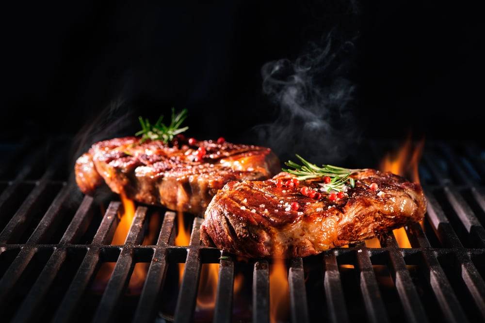 Flamegrilled steaks on a fire pit grill