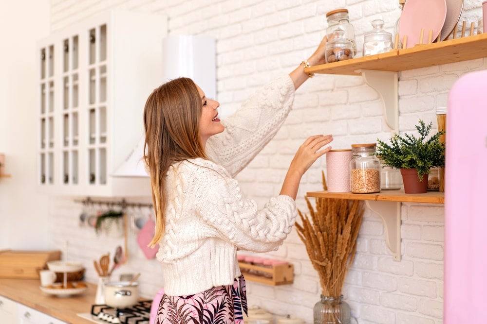 Lady organising kitchen containers on a shelf