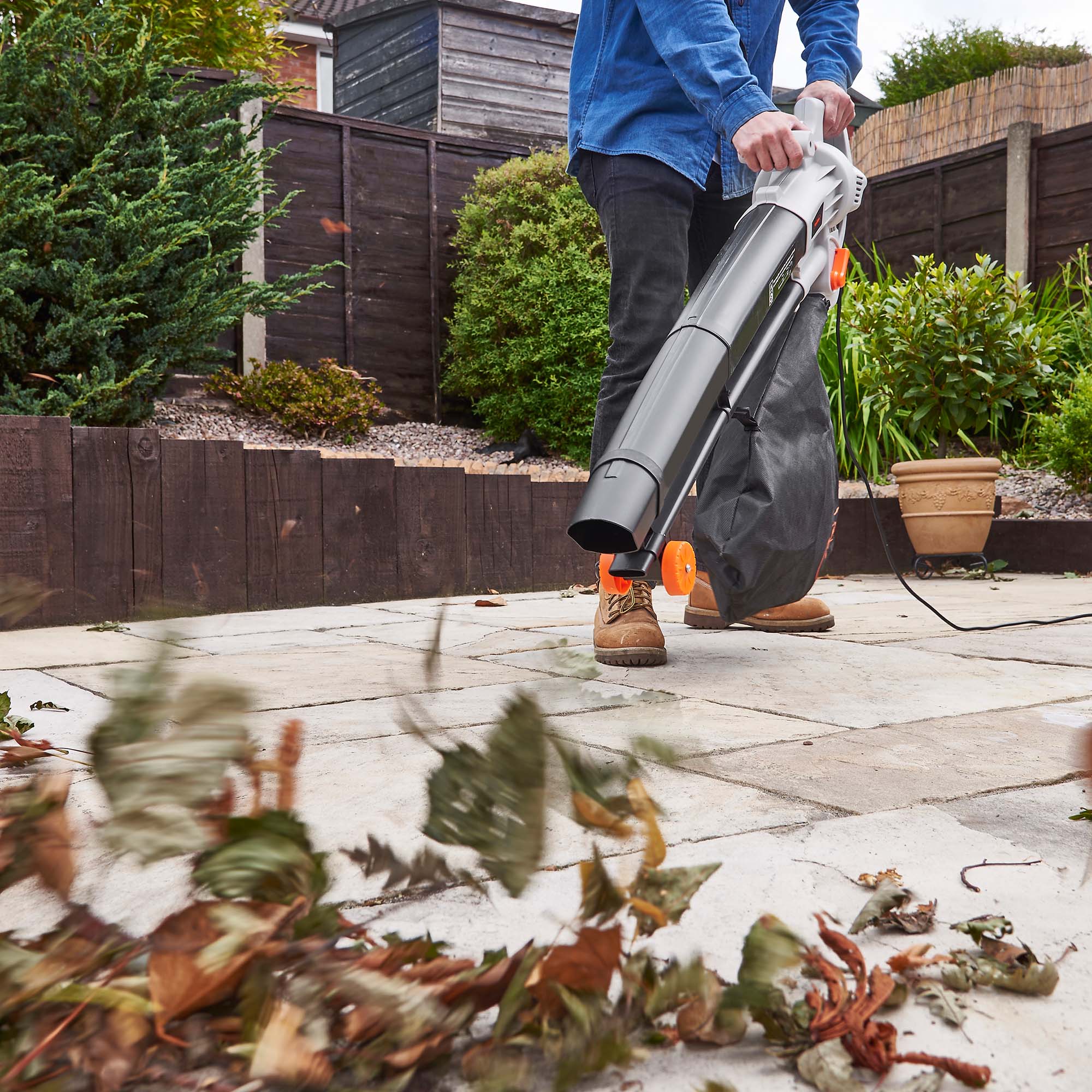 man using a leaf blower to clear leaves on a patio