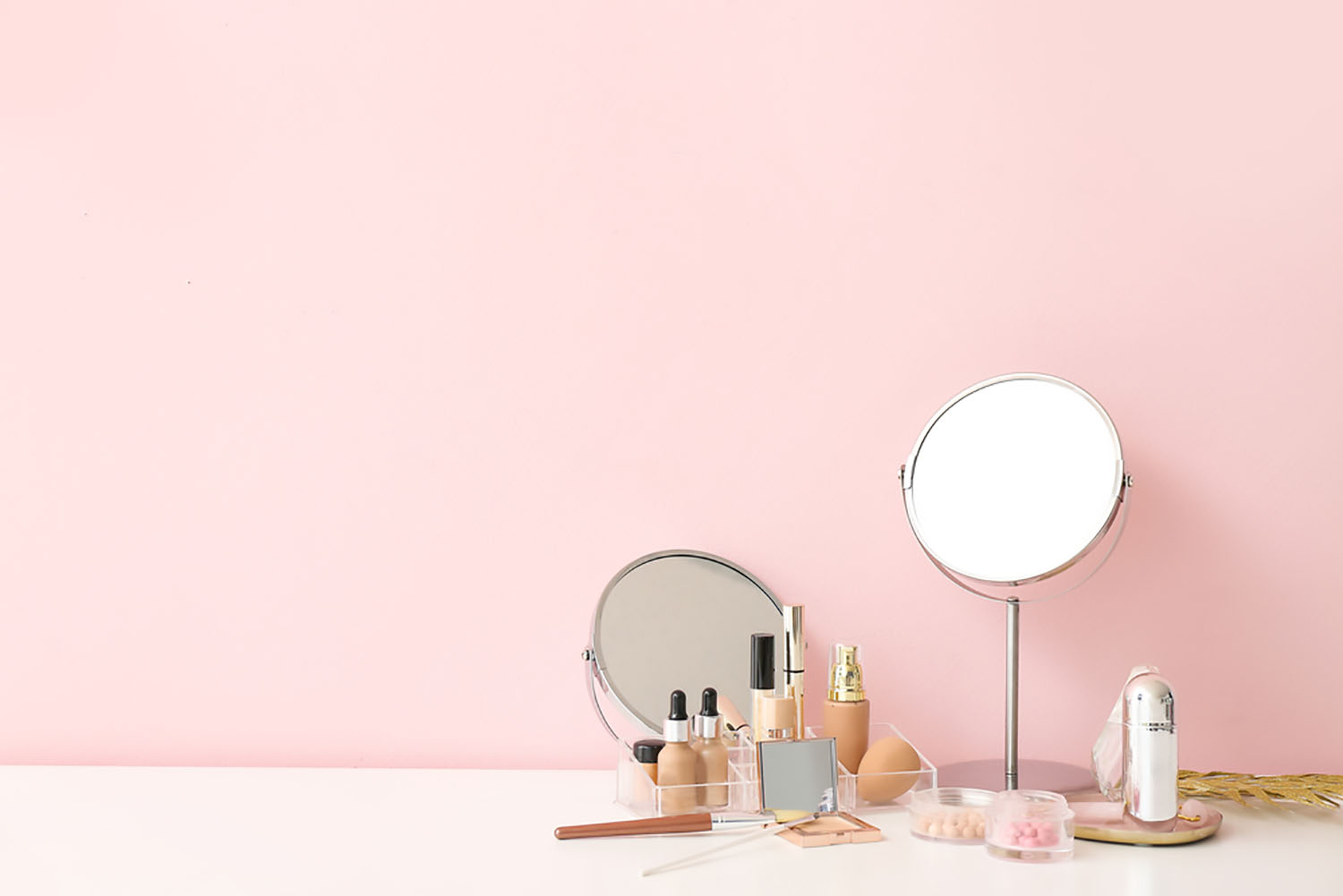 Pink dressing room containing a round mirror and cosmetics