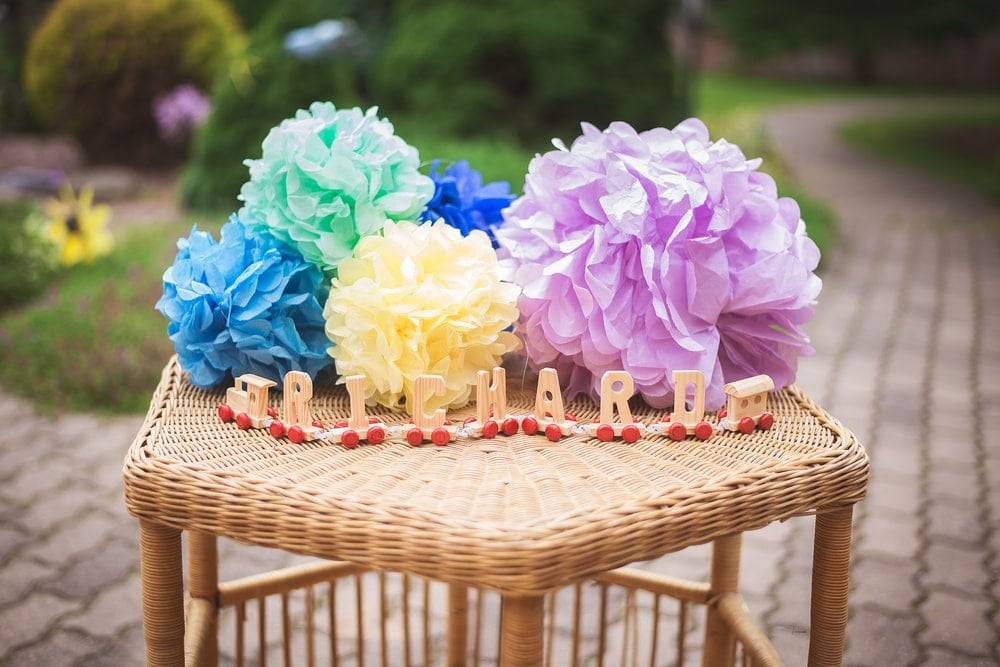 Homemade paper pom poms on a wicker table outdoors