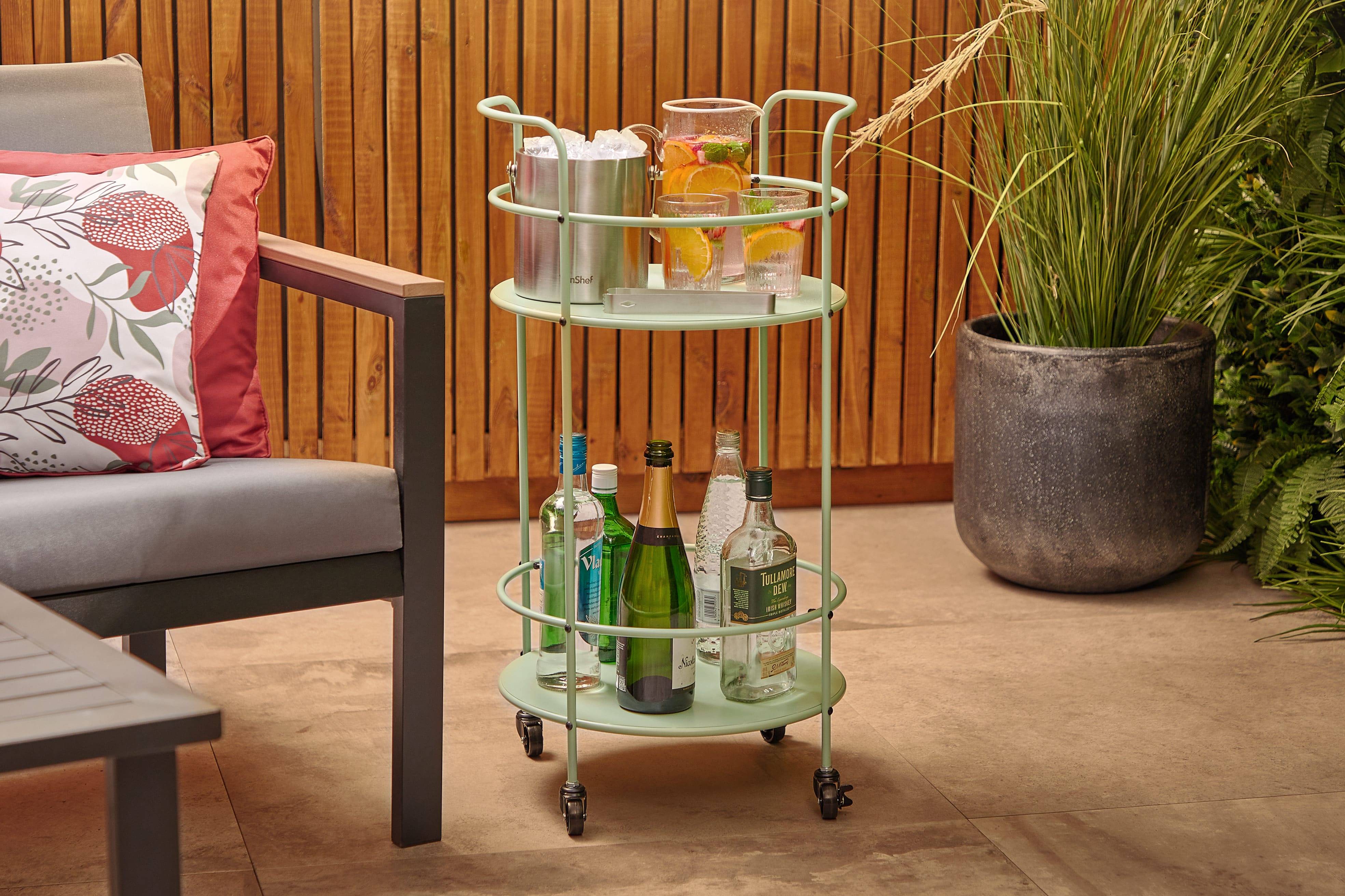 Sage green trolley holding alcoholic drinks on a patio