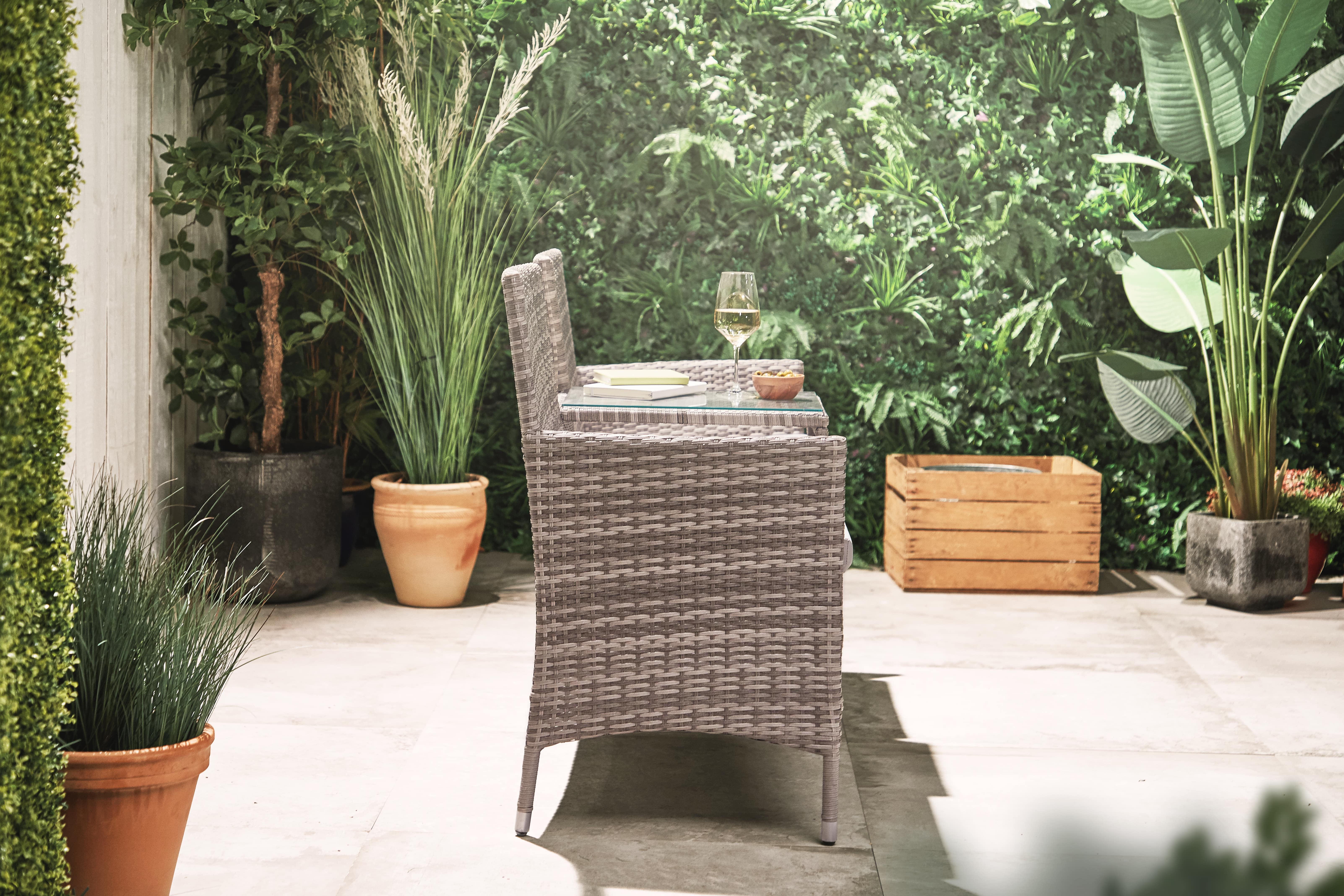 Sideview of a rattan loveseat on a wooden deck