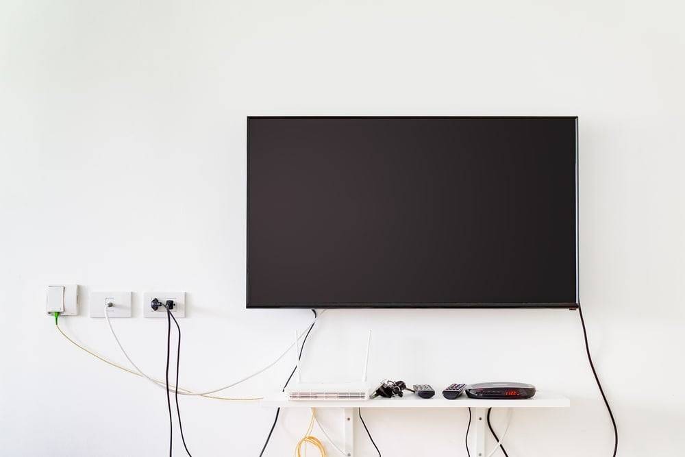 TV on a white wall with cables hanging down
