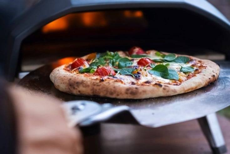 Taking pizza out of a pizza oven