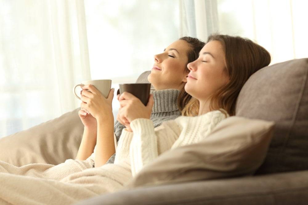 Two female roomates relaxing with a heated throw