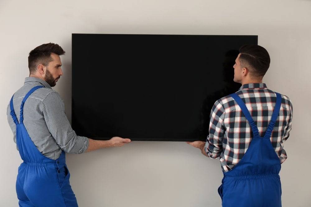 Two men mounting a widescreen TV on a wall