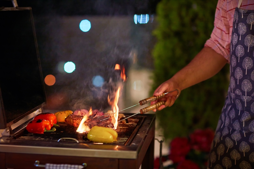 Woman grilling meat on a BBQ at night