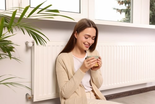 Woman smiling by a radiator