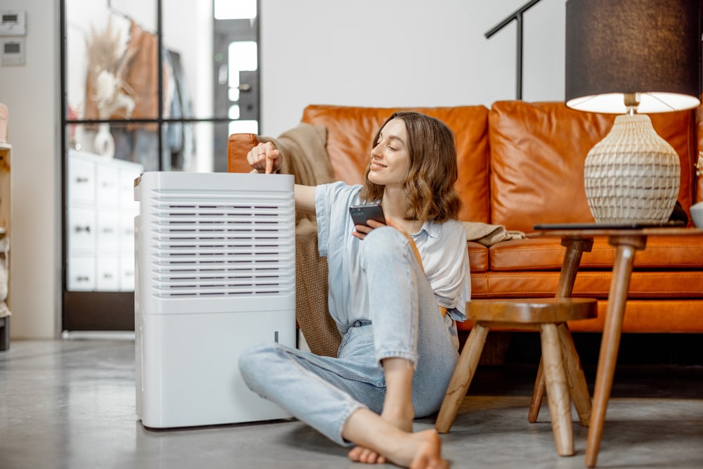 Young brunette sitting next to a dehumidifier