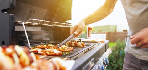 Young man grilling meats on a gas BBQ