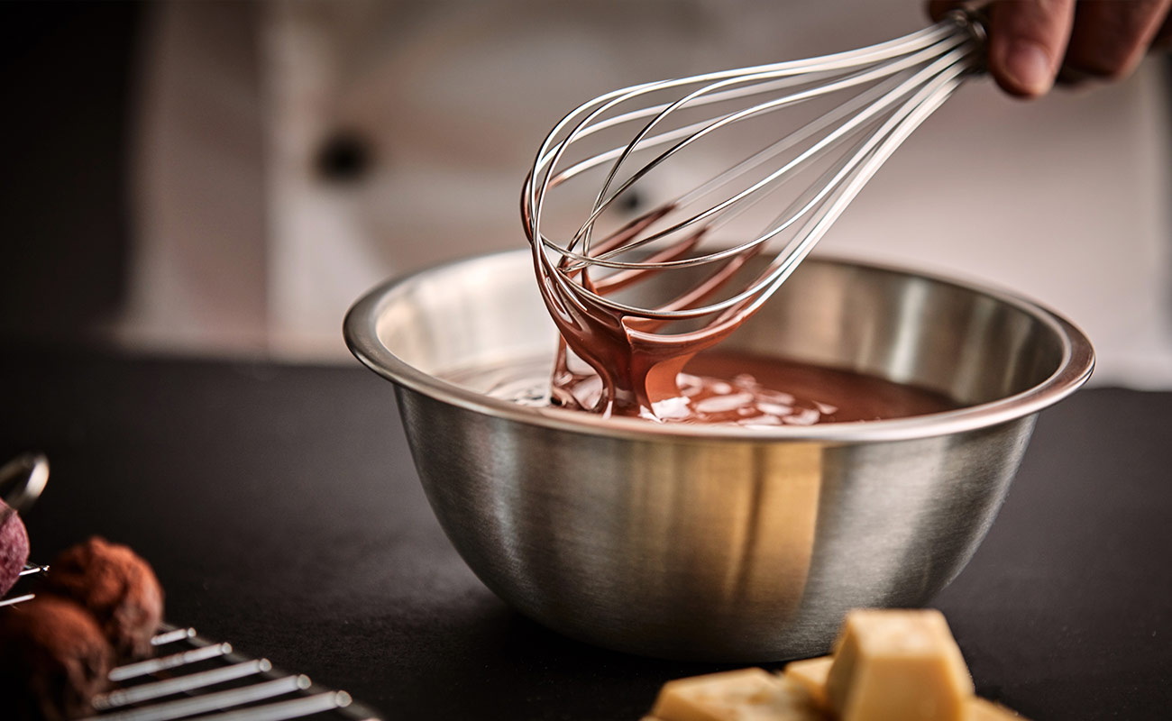 stainless steel whisk in stainless steel bowl filled with chocolate sauce in kitchen 