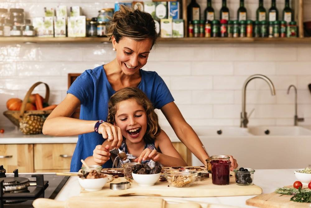 mother helping her daughter to cook ice cream in a brightly lit kitchen