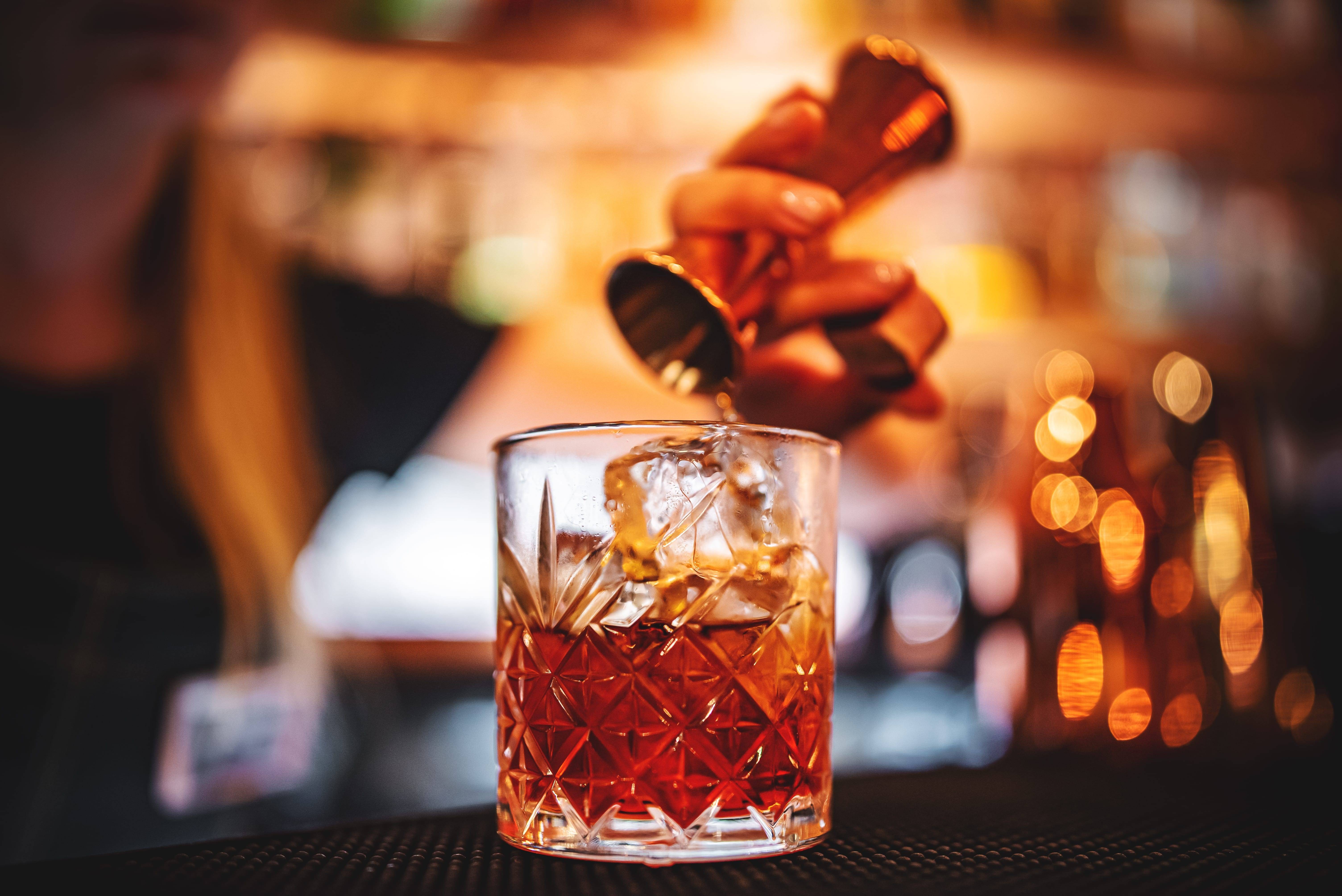 bartender pouring a shot into a negroni sbagliato