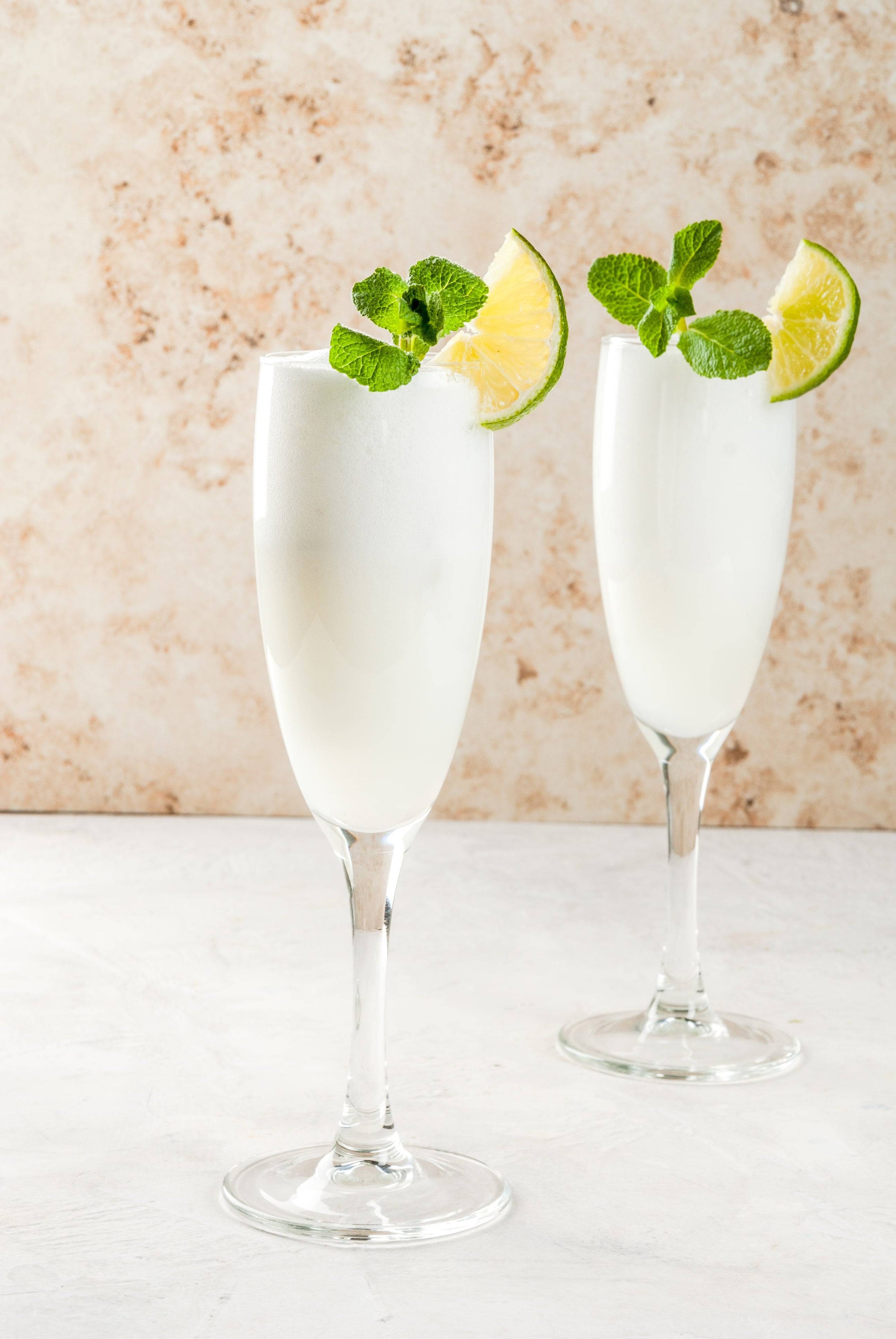 two sgroppino prosecco lemon sorbets in champagne flutes garnished with mint and lime wedge