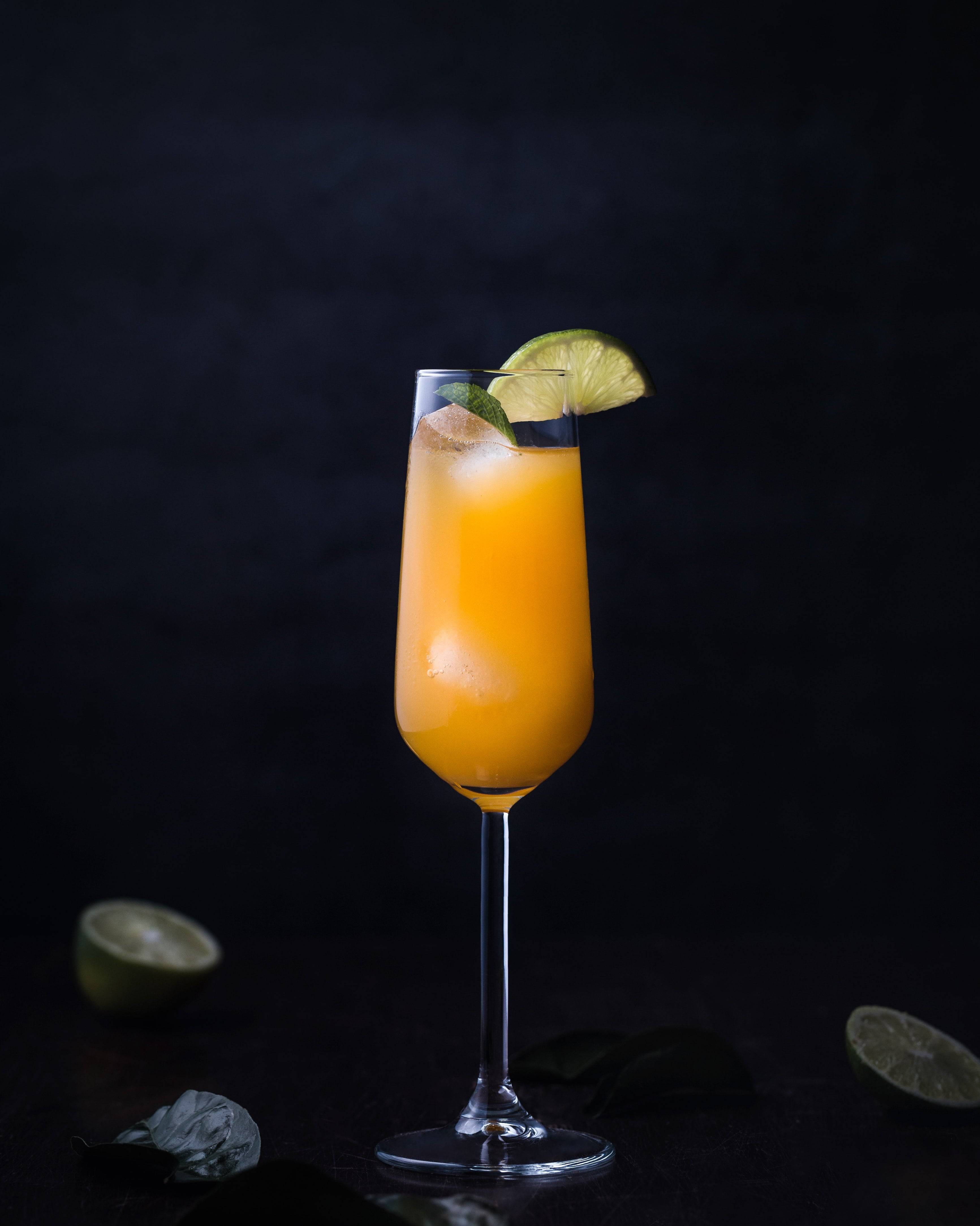 prosecco tinned peach bellini in champagne flute with lime garnish 
