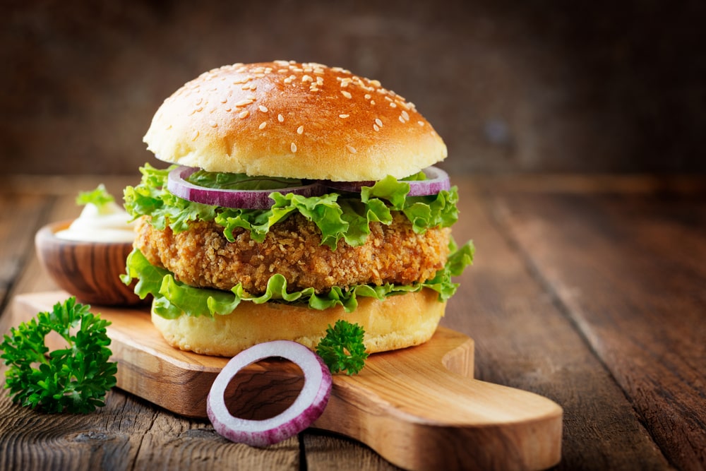 Ultimate chicken burger on a wooden chopping board